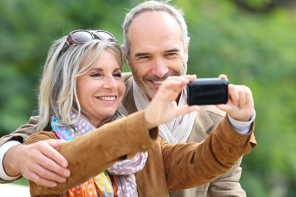 Cheerful senior couple taking picture with smartphone
