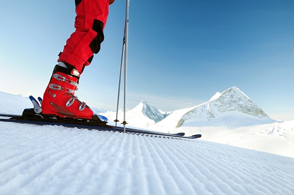 Person in ski boots and skis facing down slope