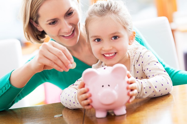 Mother and daughter putting money into piggy bank