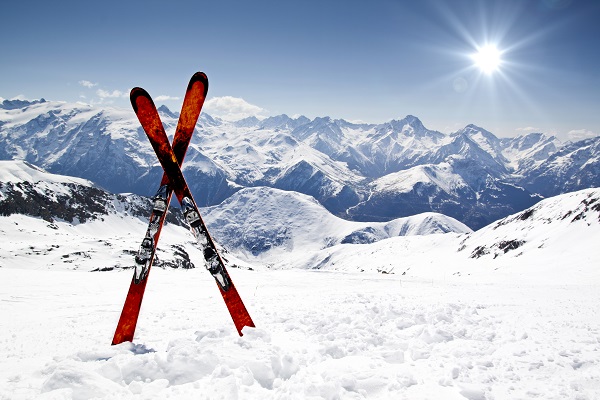 Red skis sticking out of snow with mountains in background