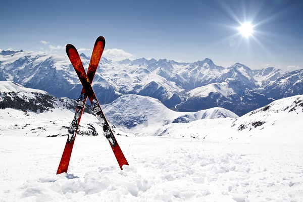 Red skis sticking out of snow with mountains in background