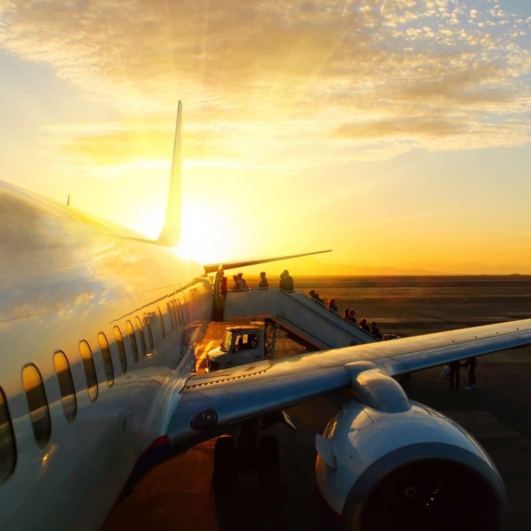 Passengers boarding airplane at sunset