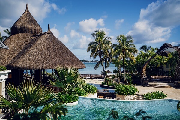 Luxury resort in Mauritius with a swimming pool, palm trees and thatched huts