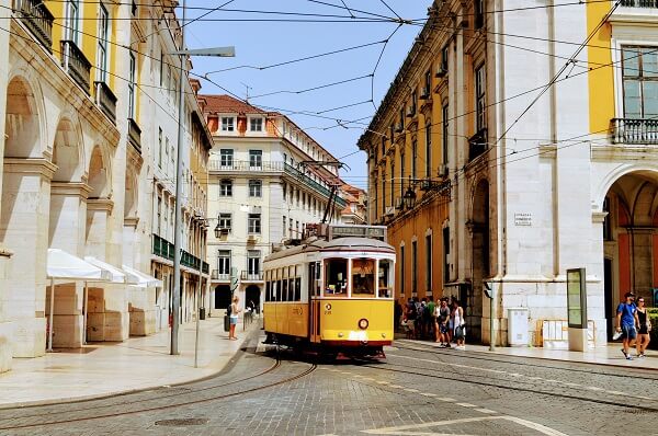 yellow tram driving through the streets of portugal